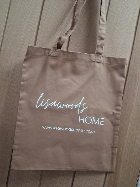 Brown fabric bag with 'lisawoods HOME' branding on a wooden surface